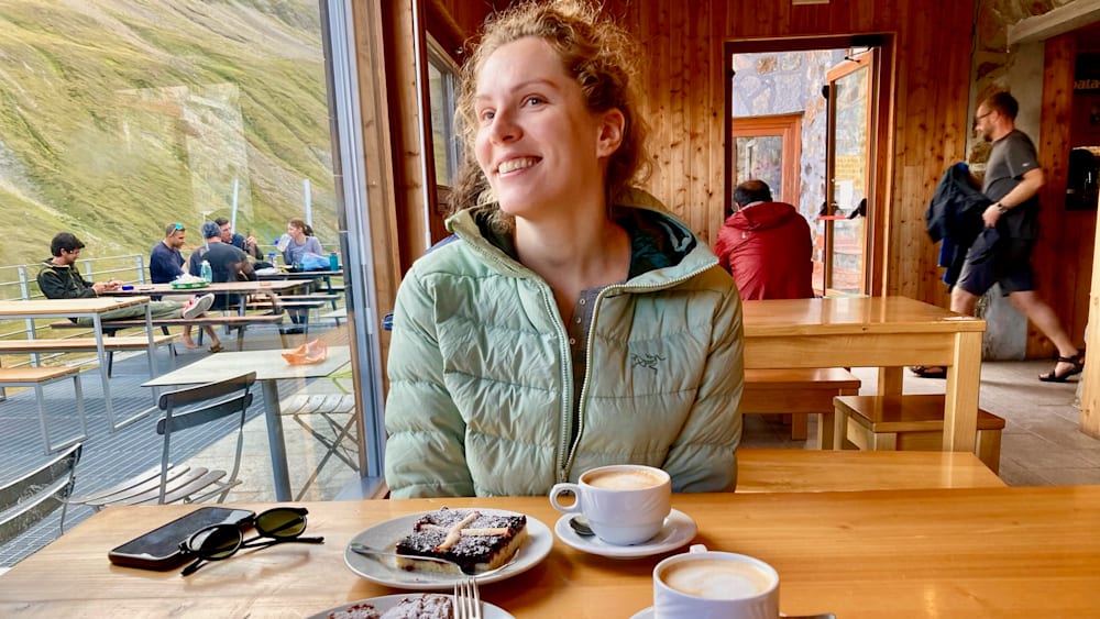 A girl is sitting at a table with a dessert and a cup of coffee.