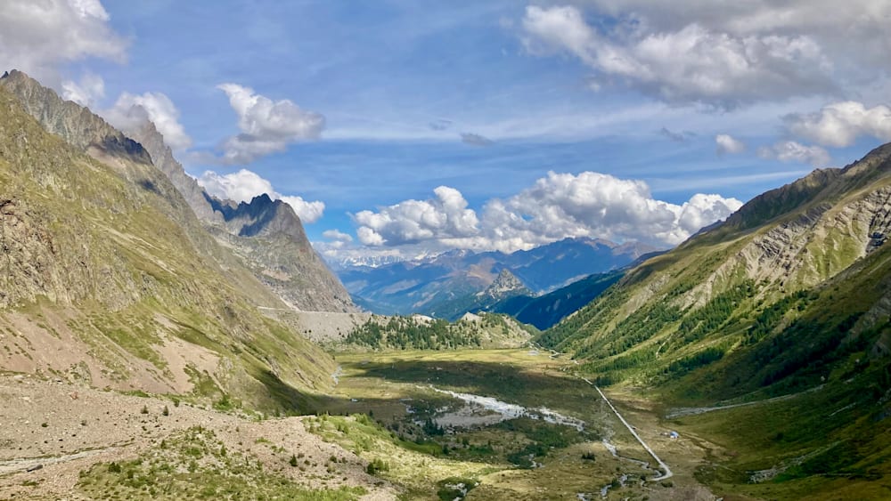 A valley with mountains in the background covered in grass.