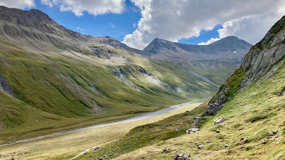 A mountain with a river running through it and a large field on either side.