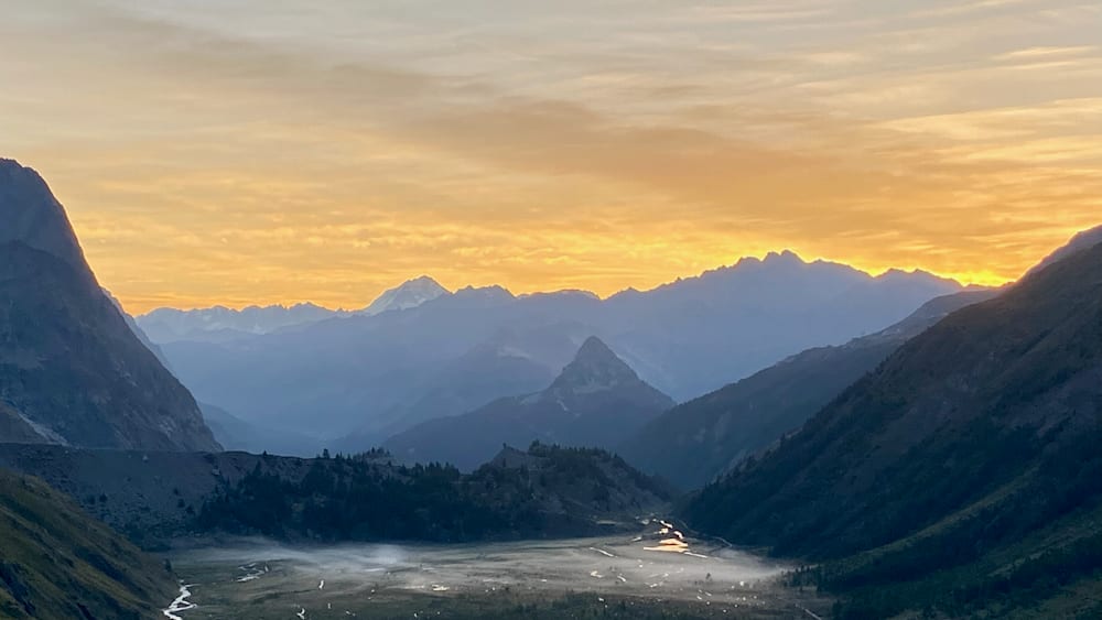 A view of mountains at sunset with a lake in the valley below.