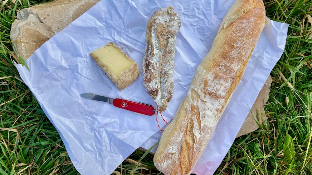 A knife and some bread are on a piece of paper.