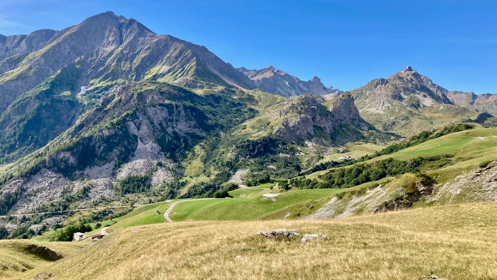 A mountain with a road going through it and a field with a rock in it.