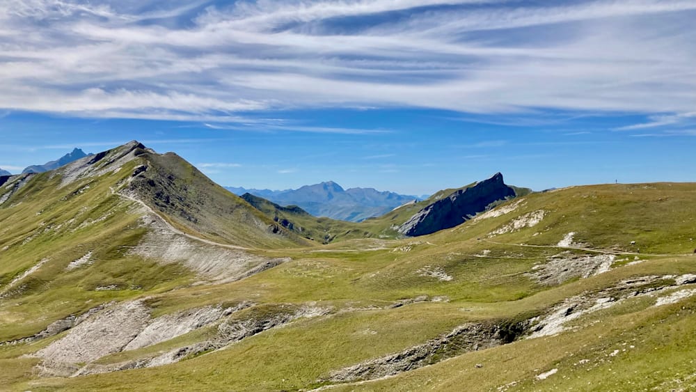A valley with mountains in the distance and a large body of water is shown.