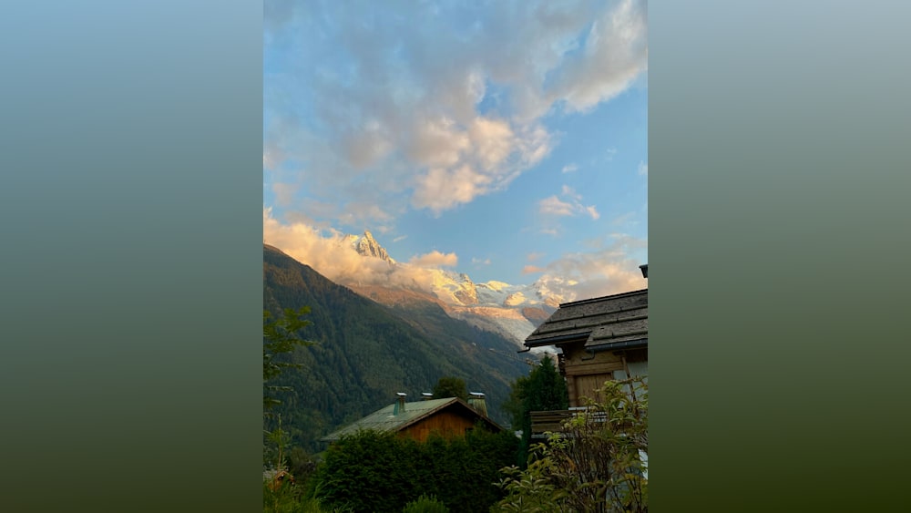 A beautiful view of mountains and clouds with a wooden house in the background.