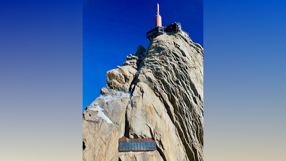A rocky mountain with a glass building on top.