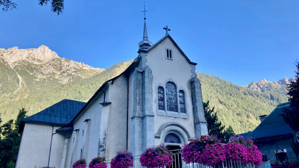A church with a large cross on top of it and has a blue sky in the background.