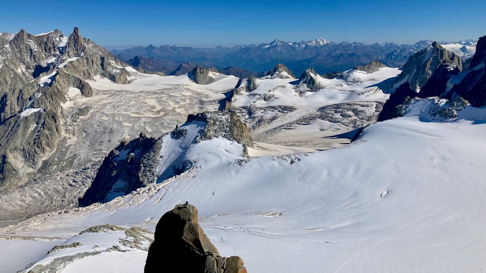 A large rock is visible in the foreground of a snow covered landscape.