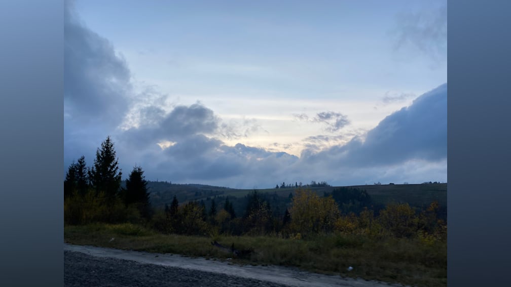 The sky is blue with clouds and trees in the background.