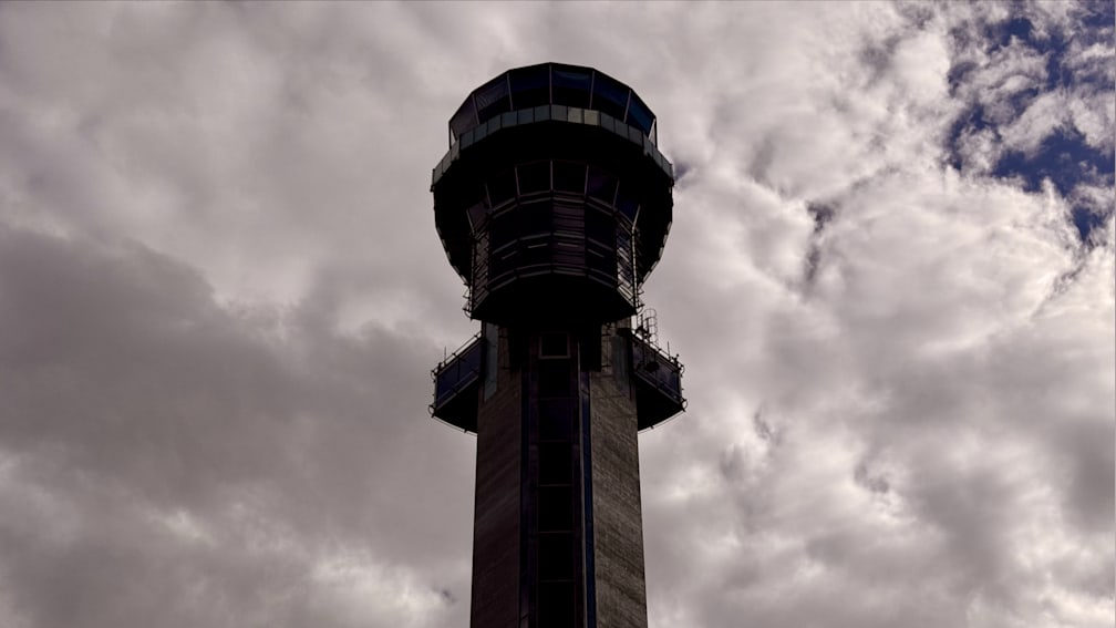 A tall tower with windows sits in the sky under a cloudy gray sky.