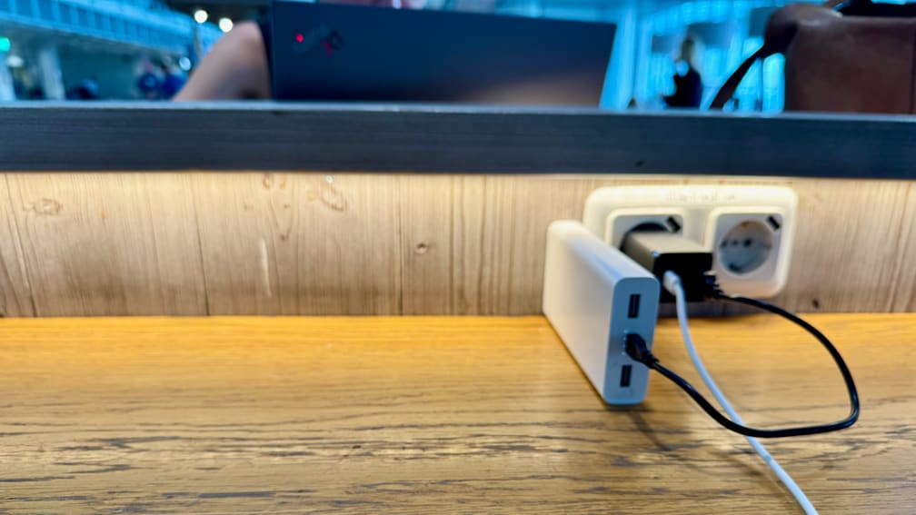 A white charger with two plugs in a brown table.