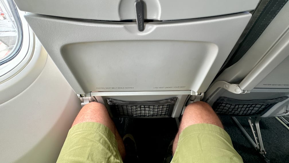 A person with their seat belt fastened, with the belt visible under the seat.