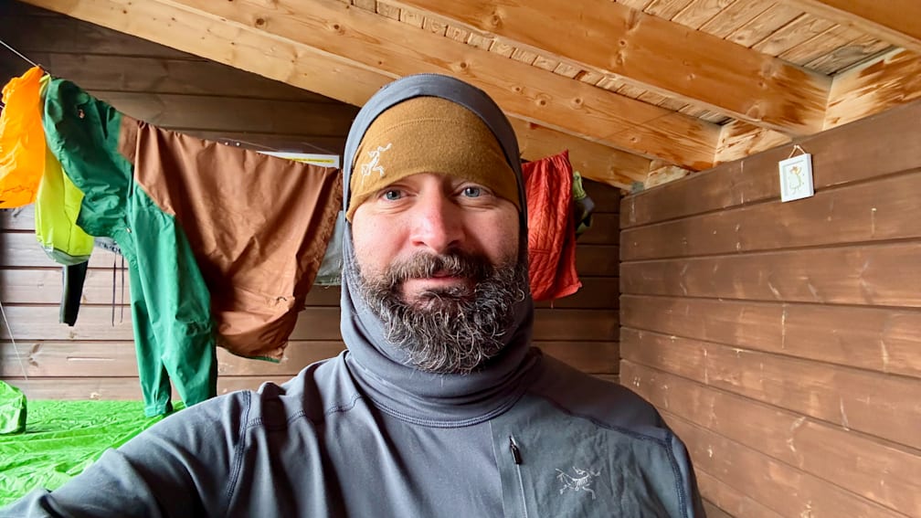 A man wearing a brown and gray shirt is taking a picture of himself.