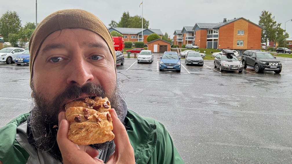 A man eating a pastry in the rain.