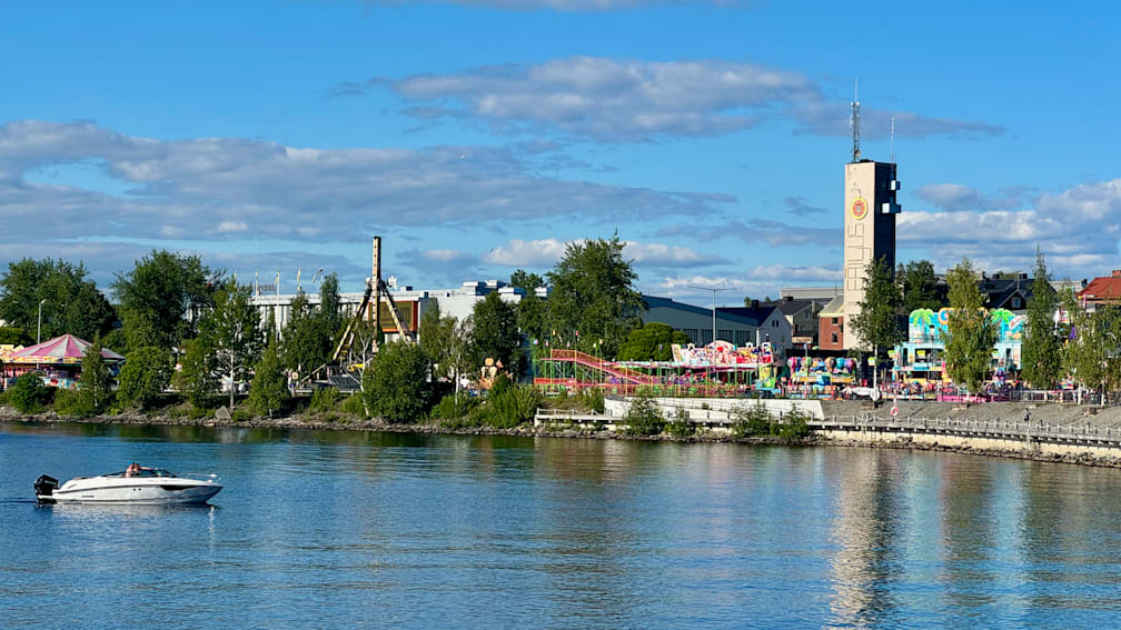 A body of water with a ferris wheel and other rides near the shore.