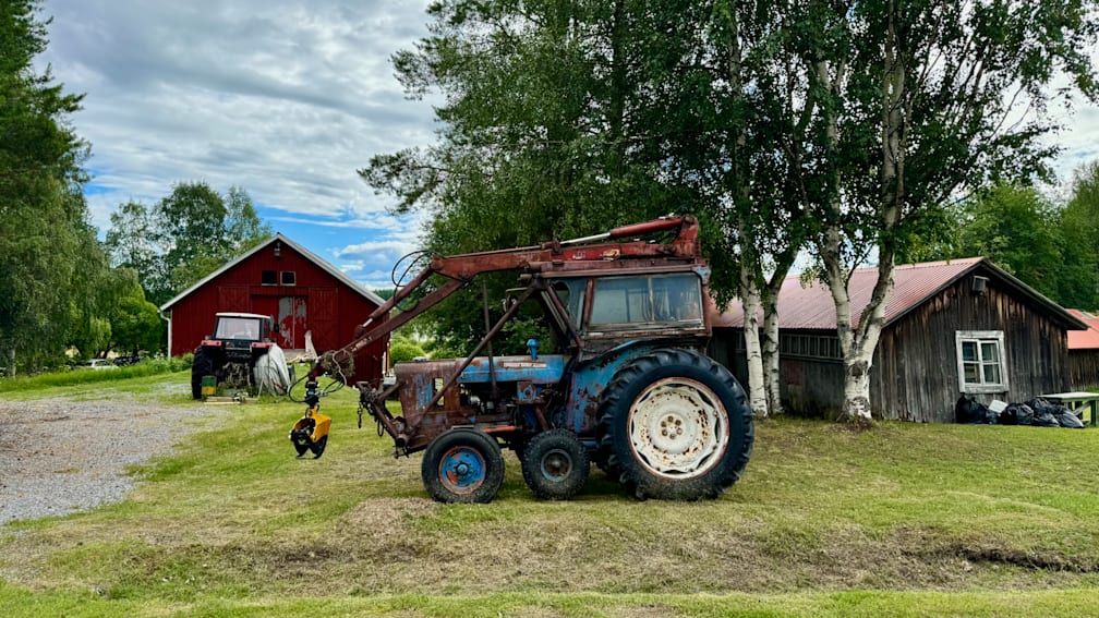 An old tractor with four wheels sits in a field.