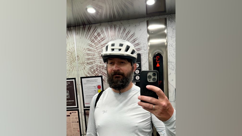 A man wearing a helmet takes a picture of himself in the mirror.
