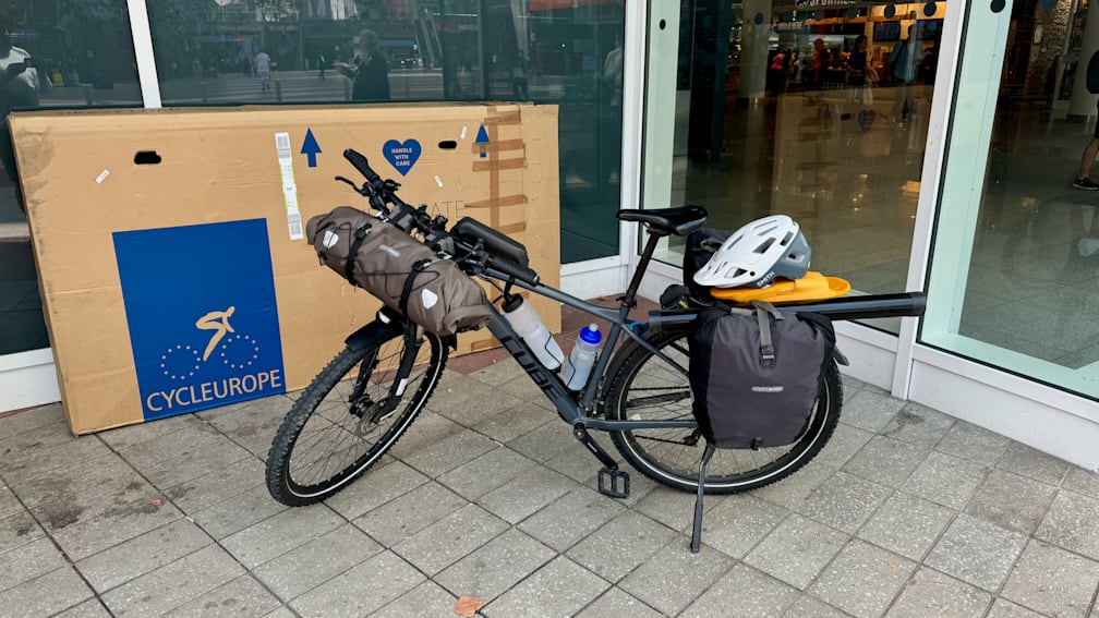 A bike with a water bottle and helmet on the back of it outside of a building.