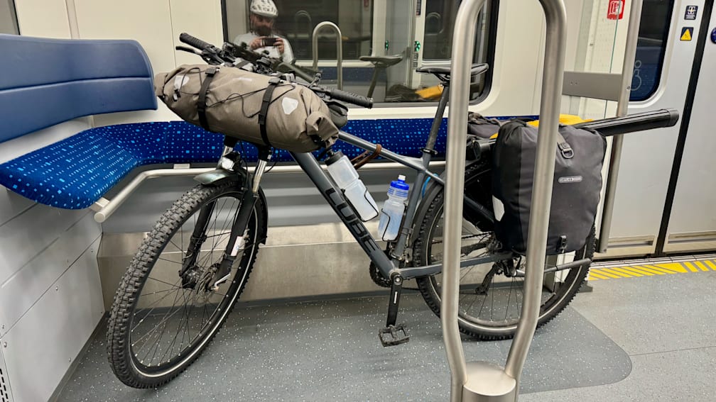 A bike with a water bottle on it and a metal pole next to it on a subway train.