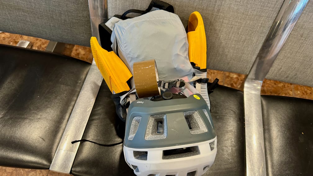 A helmet is strapped to a pack on a chair.