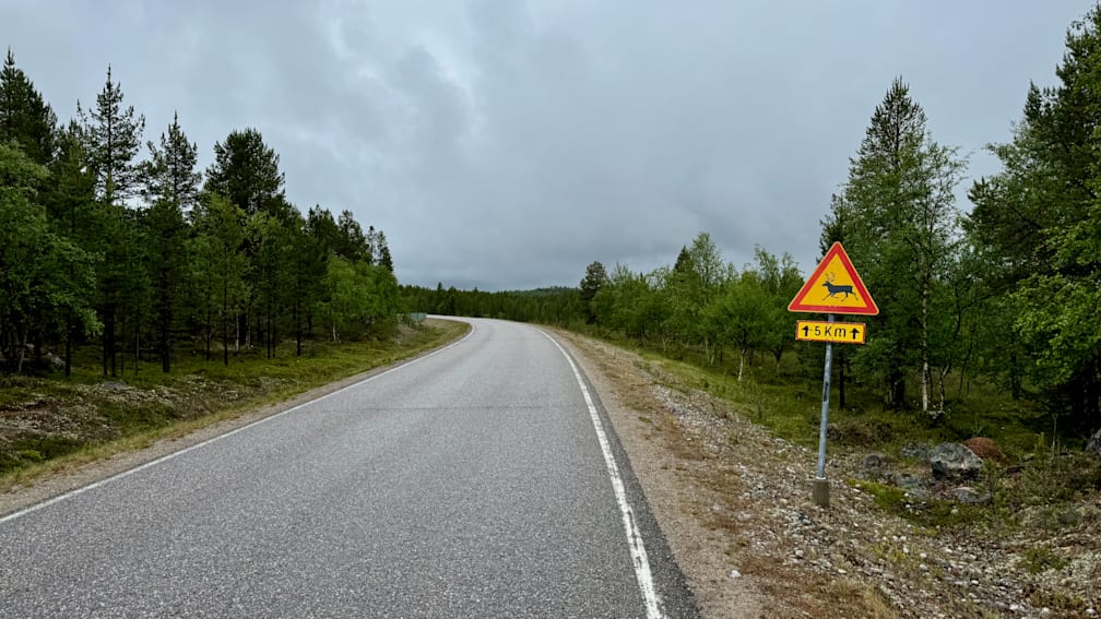 A warning sign is on the side of a road that is very quiet.