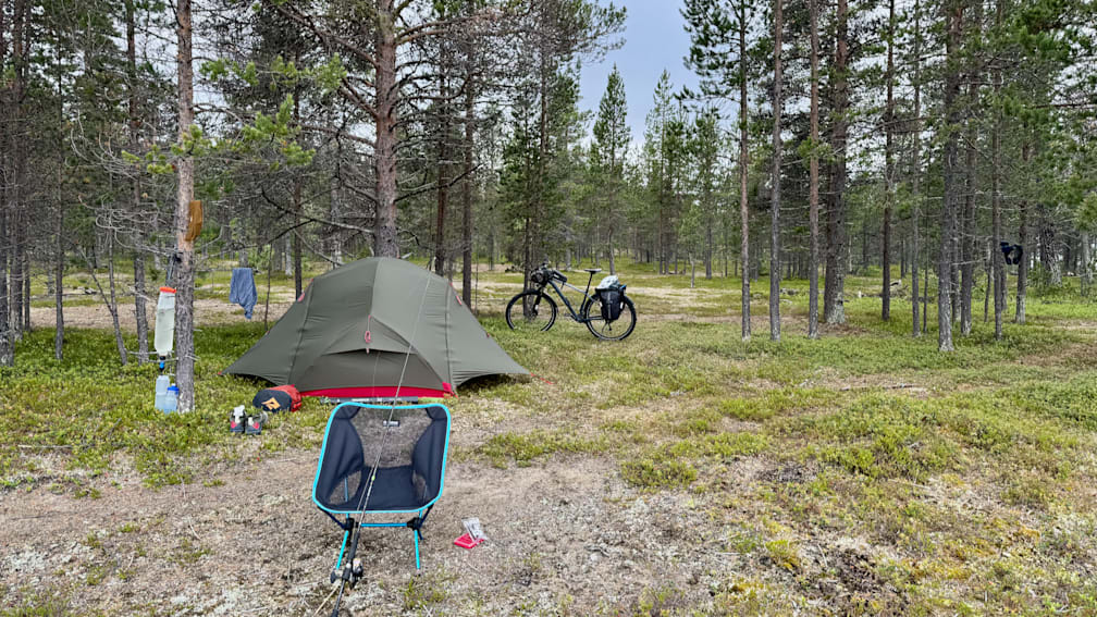 A chair and a bike are set up in a campsite.