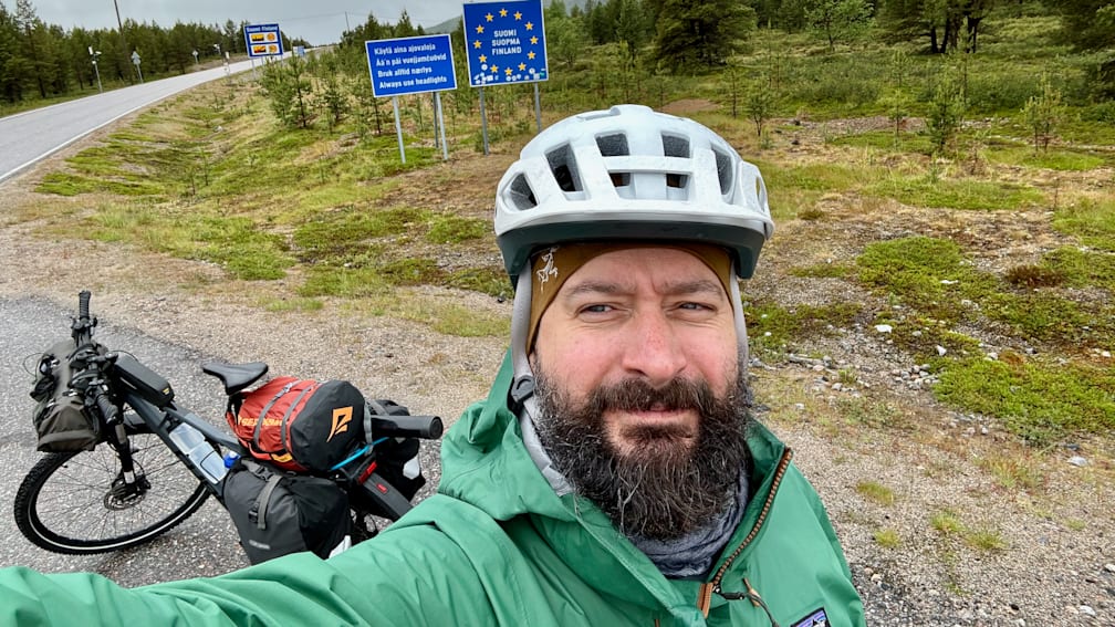 A man wearing a green jacket and a white helmet is taking a picture of himself.