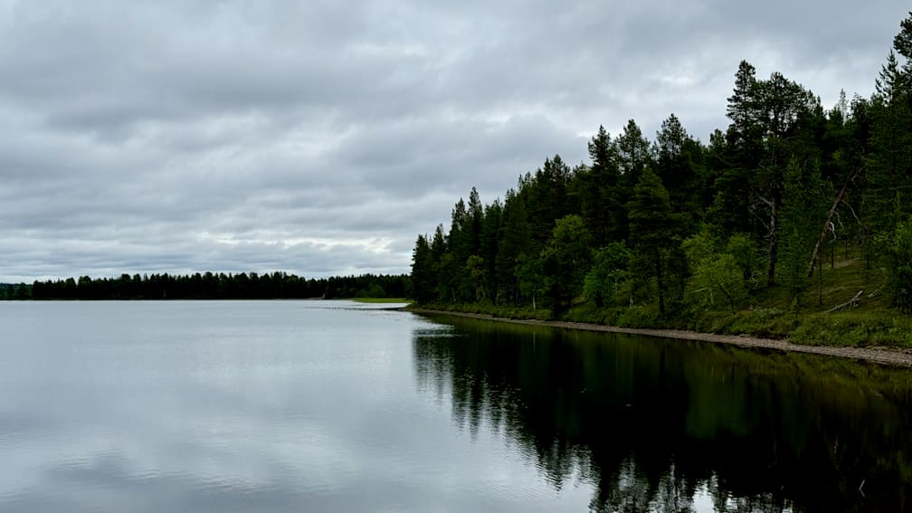 A lake surrounded by trees and with a reflection in the water.