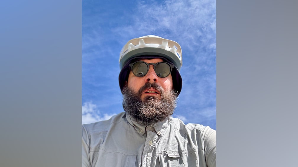 A man with a beard and a helmet in front of him.