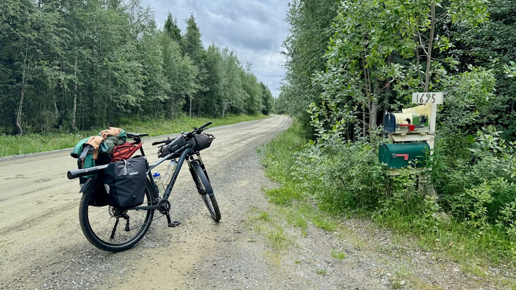 A bicycle is sitting on the road next to a mailbox.
