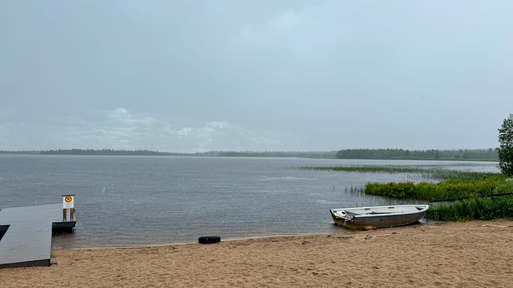 A boat is sitting on the beach next to the water.