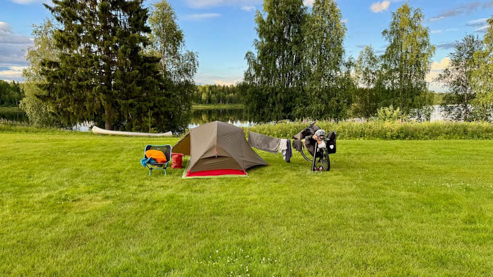 A tent is set up on a grassy area with a bicycle nearby.