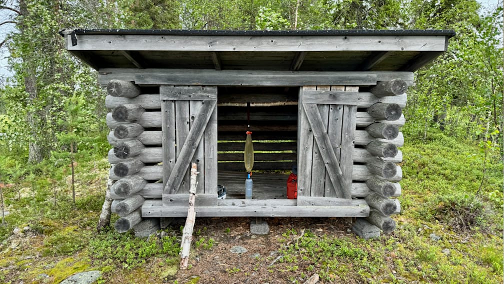 A log cabin with a bottle in the window and a radio outside.
