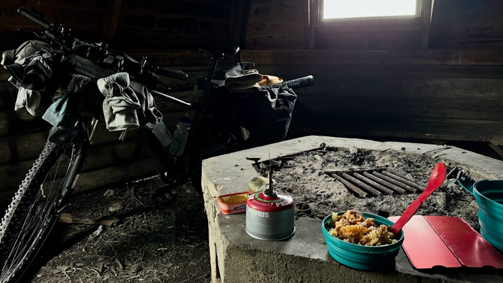 A Primus gas can is sitting on a concrete slab with a bowl of food next to it.