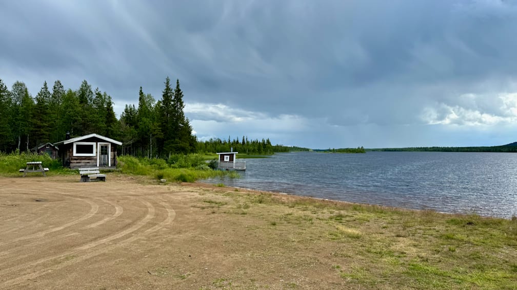 A small cabin is docked at the shore of a lake on a stormy day.