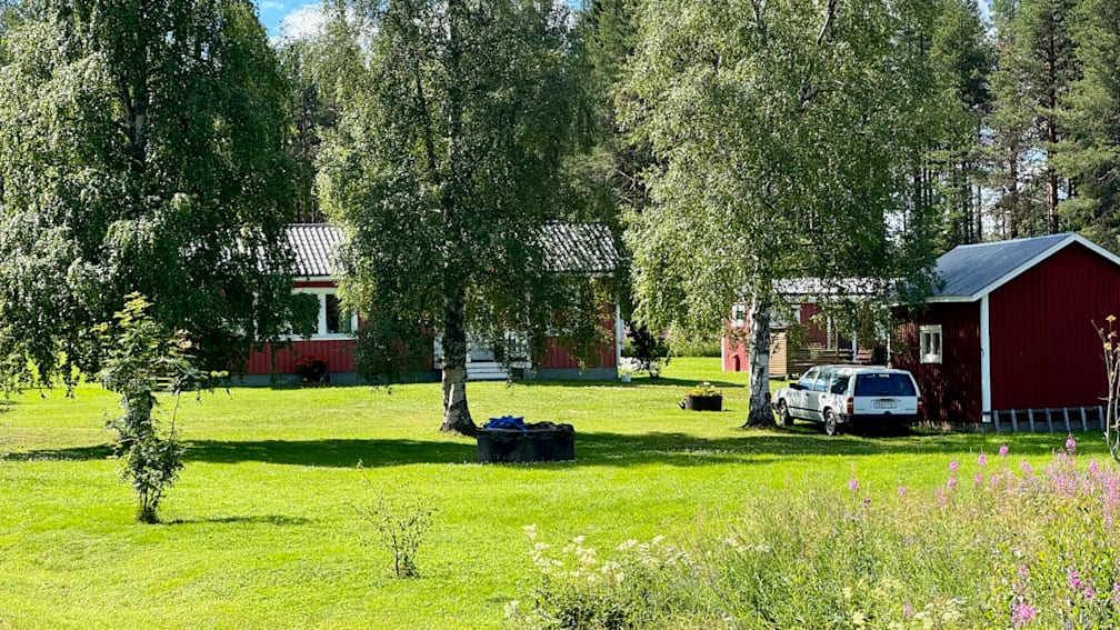 A white truck is parked in front of a red house.
