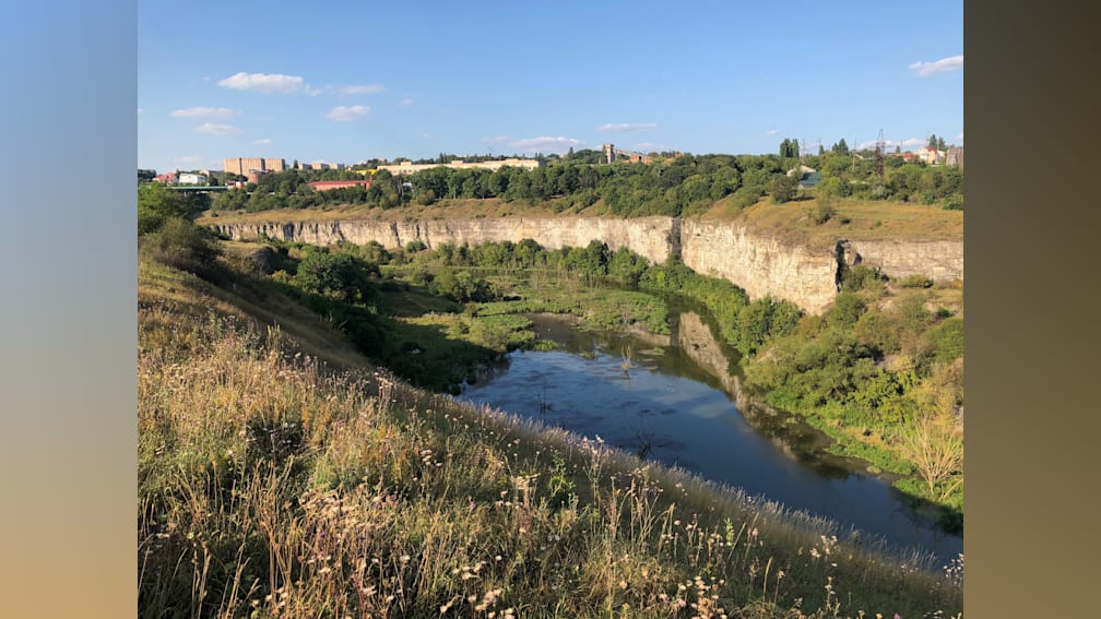 A river flows through a field and pastures before it empties into a lake.
