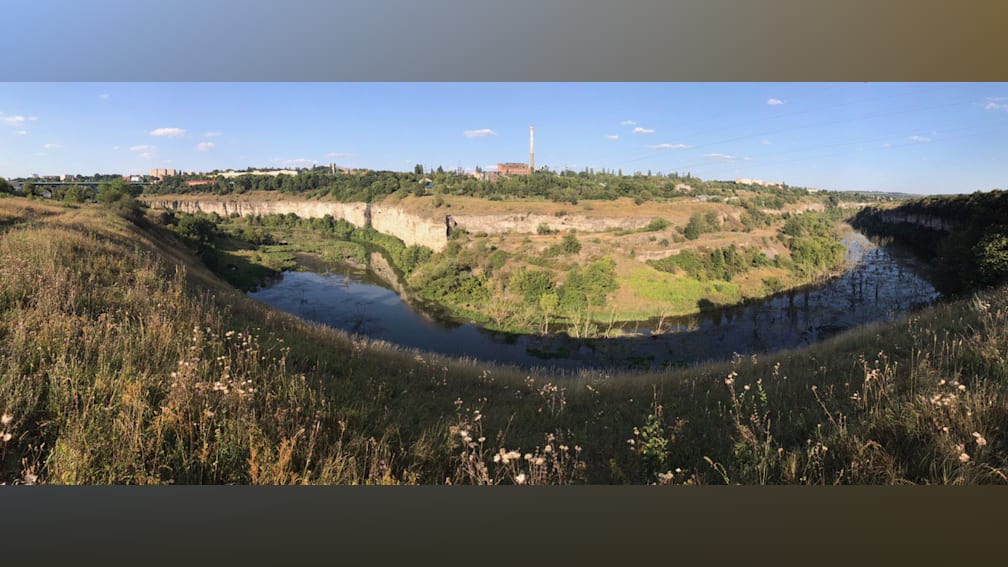 A long shot of a river with a cliff in the background.