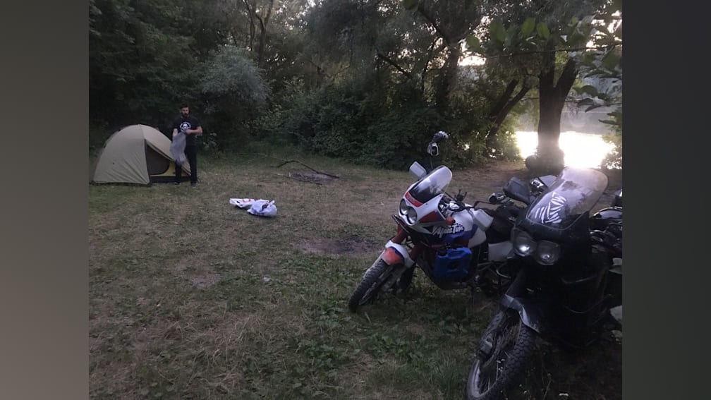 A man is standing next to a motorcycle in a field.