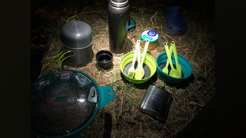 A camping stove and other supplies are set up on the grass.