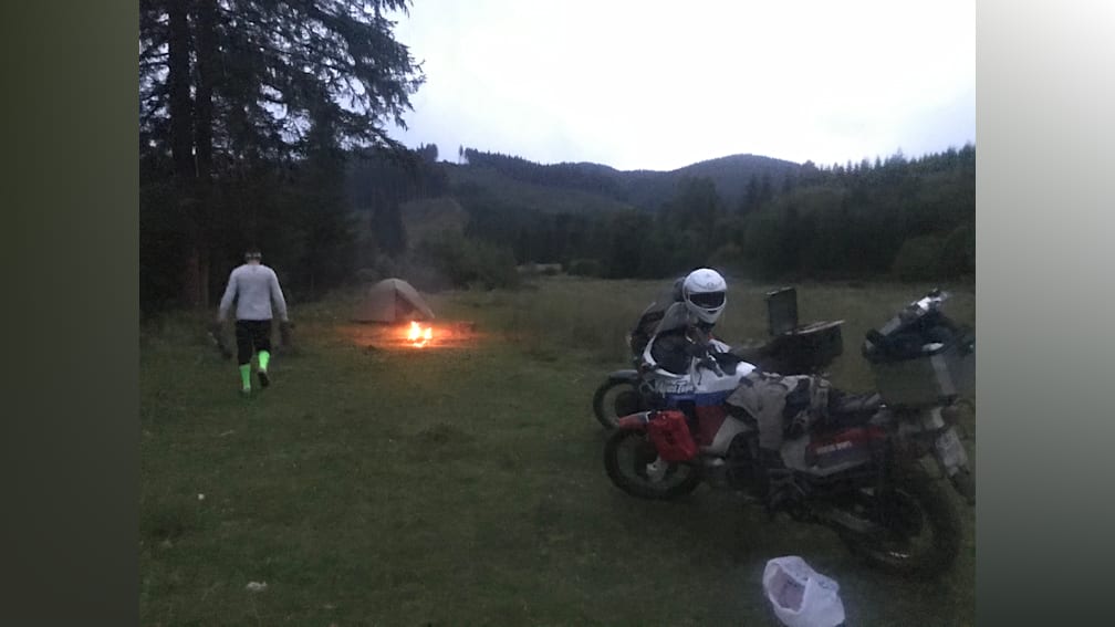 People are camping in the outdoors and have their bikes parked nearby.