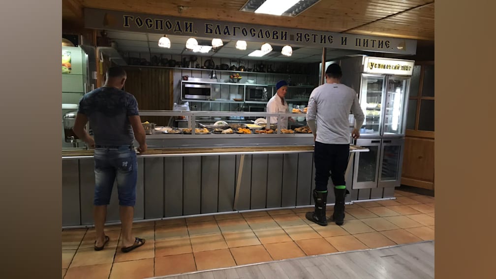 People are waiting in line at a deli counter that is covered in food.