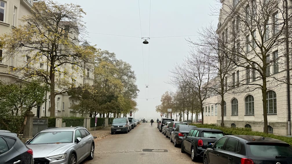 A street scene with many parked cars on the side of the road.