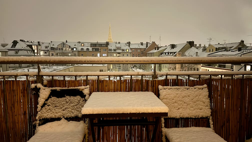 A view of a city from a balcony covered in snow.