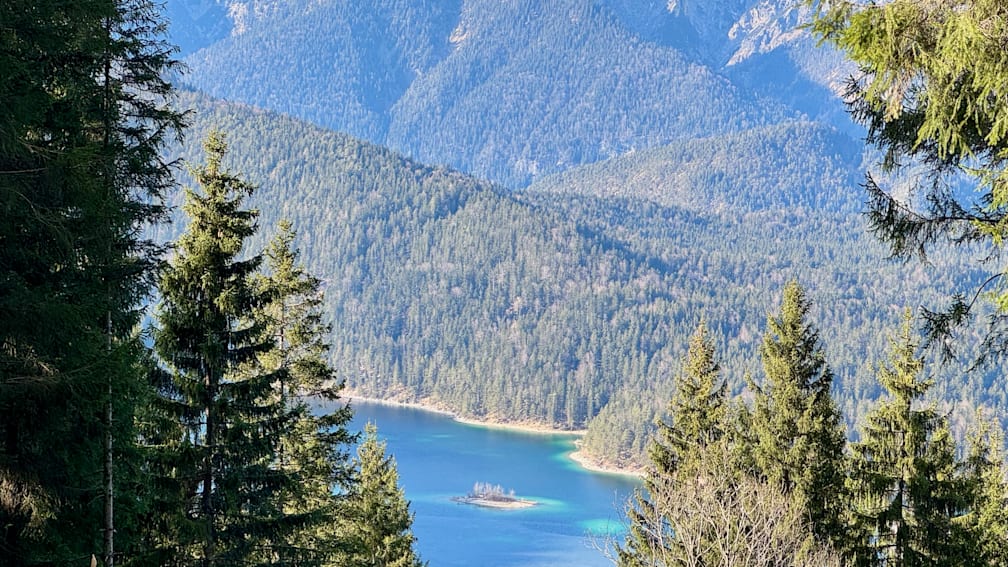A lake is surrounded by trees and mountains and is blue in color.
