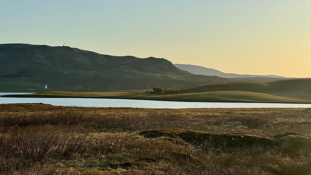 A field with a small house in the middle of it.