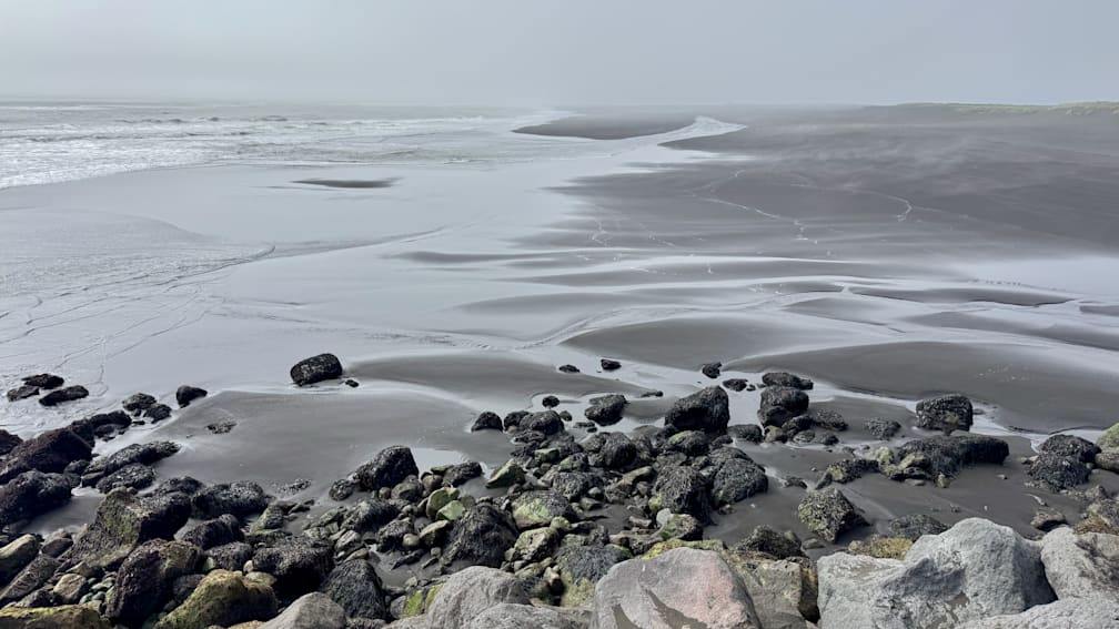 A black and white photo of a beach with waves crashing on it.