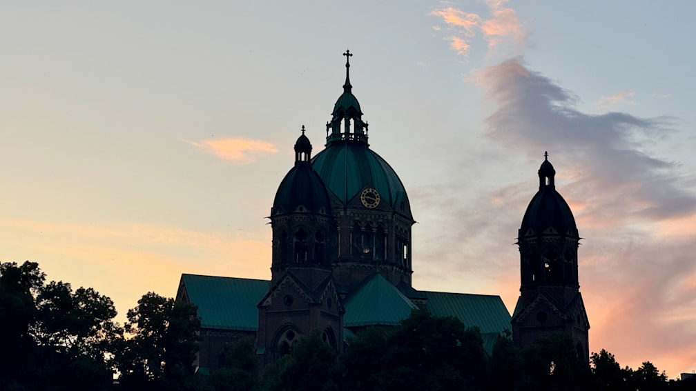 A church with a clock that is lit up in the night sky.
