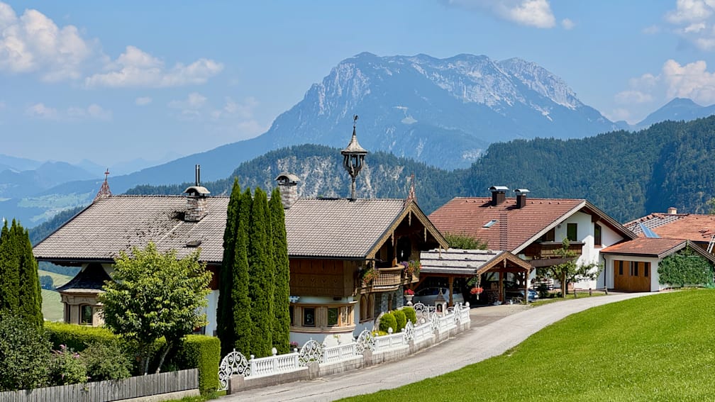 A road goes by a row of houses with trees in it.