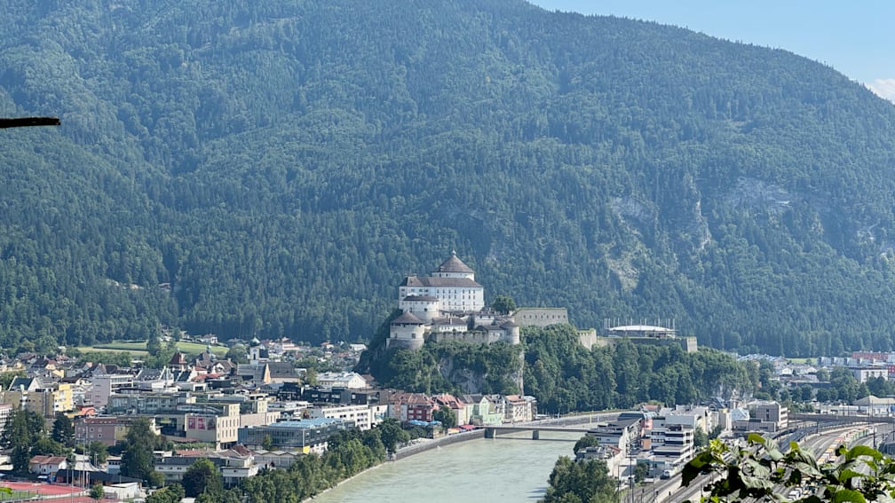A river runs through a town with a castle on its hill.