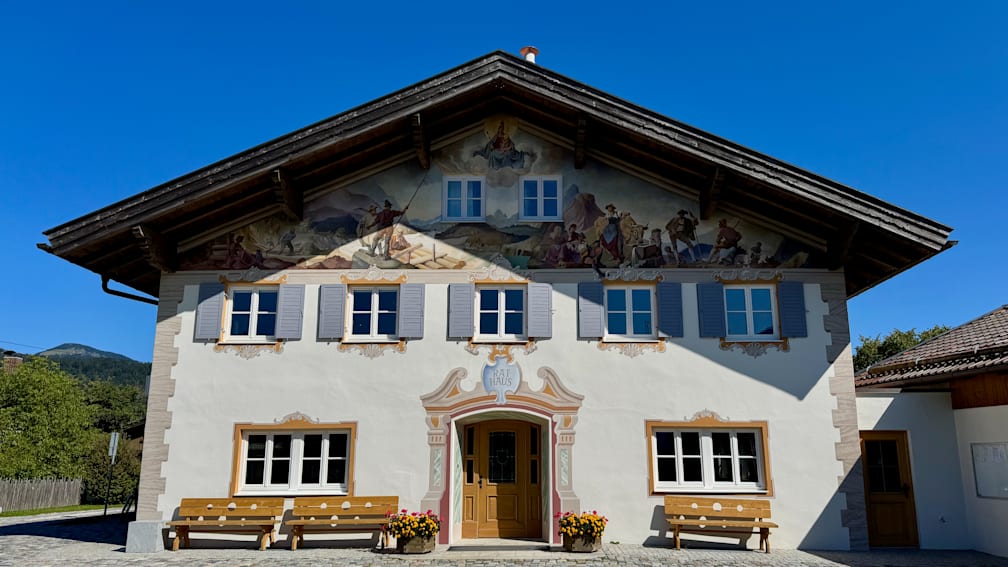 A white building with colorful paintings on it and a sign that says "Raeae".